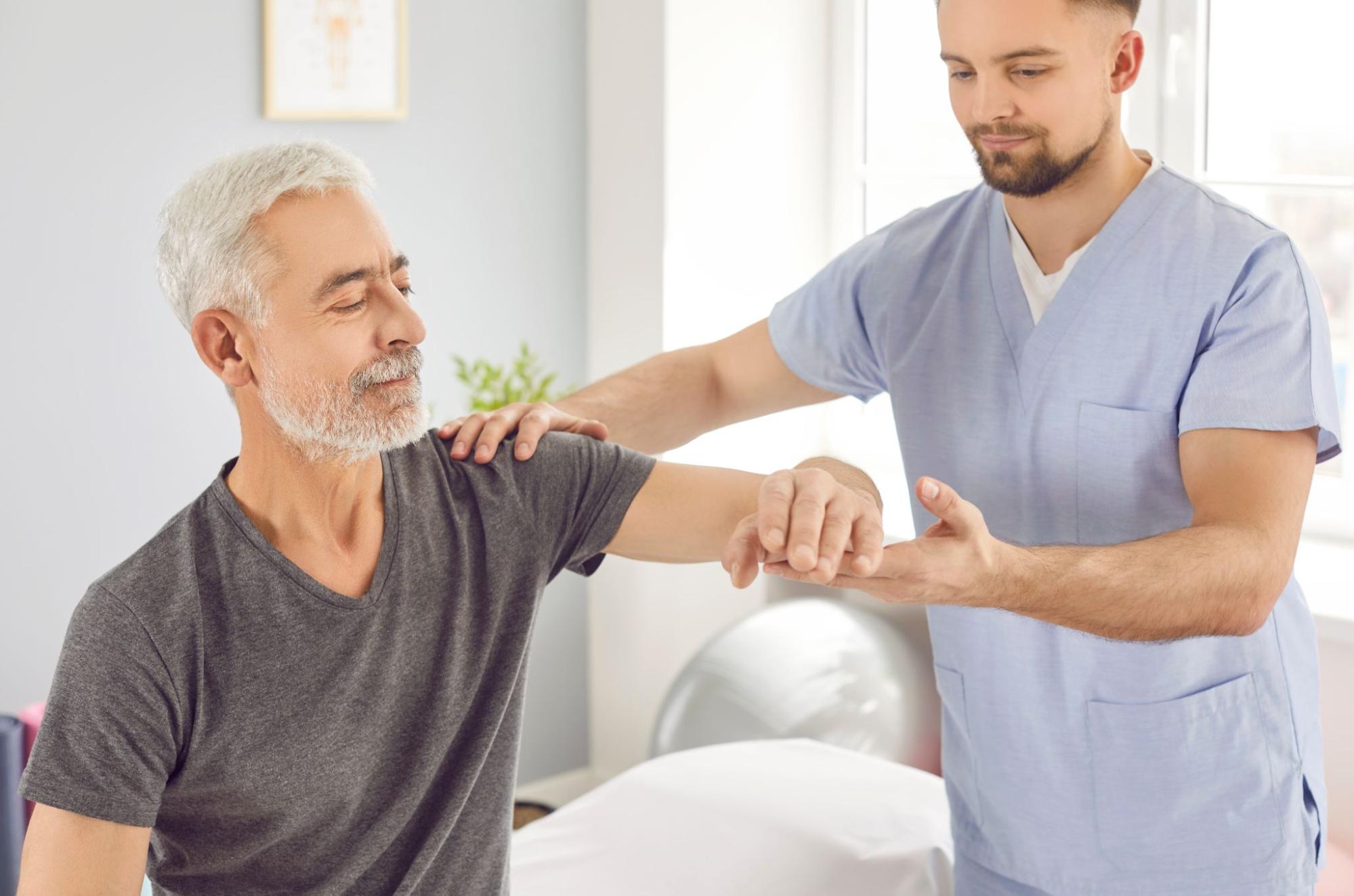 An assisted living nurse helps an older adult with physiotherapy exercises after a stroke.