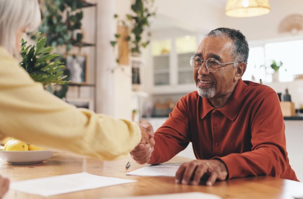An older adult shakes hands with a caregiver in an assisted living community